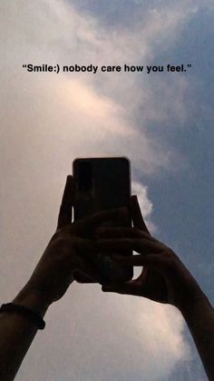 someone holding up their cell phone to take a photo with the sky in the background