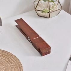 a wooden box sitting on top of a white table next to a vase with flowers