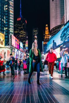 a woman is walking down the street at night in times square, new york city