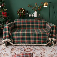 a couch covered in a plaid blanket next to a christmas tree