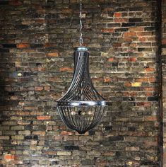 a chandelier hanging from the ceiling in front of a brick wall and floor