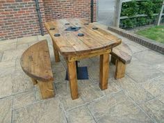 a wooden table with two benches next to it on a brick patio near a building