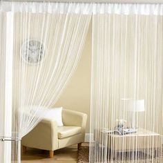 a living room with white curtains and a chair