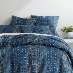 a bed with blue and white bedspread, pillows and pillow cases on it