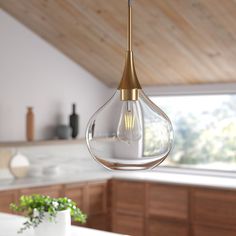 a light fixture hanging from the ceiling in a kitchen with white counter tops and wooden cabinets