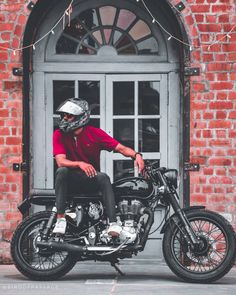 a man sitting on top of a motorcycle in front of a building with an open door