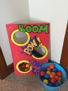 a blue bowl filled with gumballs next to a cardboard box that says boom on it