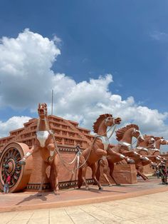 several large sculptures in the shape of horses and chariots on display at an amusement park