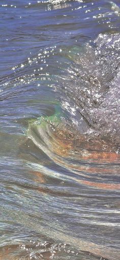 an ocean wave with small white bubbles coming from it