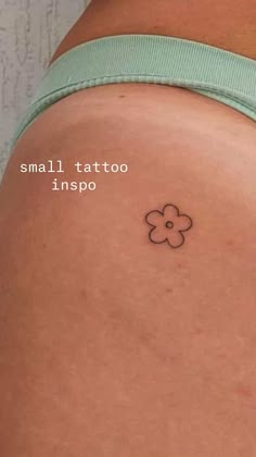 a small tattoo on the back of a woman's thigh, with an image of a flower