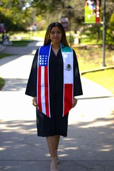 a woman is walking down the sidewalk wearing a graduation gown with an american flag on it