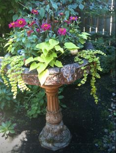 a planter filled with flowers and greenery in the middle of a garden area