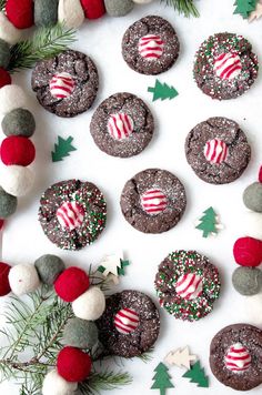 chocolate cookies decorated with candy canes and peppermints on a white surface surrounded by christmas decorations