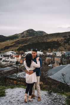 a man and woman hugging each other on top of a hill