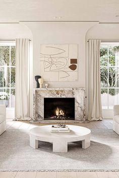 a living room with white furniture and a fire place in the middle of the room