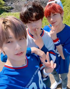 three young men standing next to each other with their fingers in the shape of two peace signs