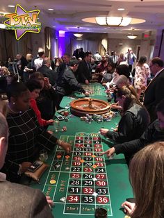 people playing roulend at a casino table in a room full of other people