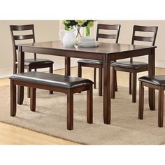 a dining room table with four chairs and a bench in front of it on a rug