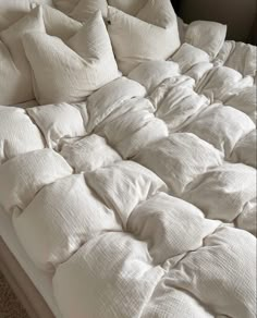 an unmade bed with many pillows on it