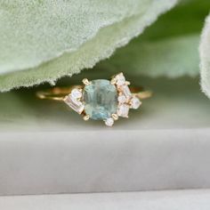 a close up view of a ring with an aqua blue stone and two white diamonds