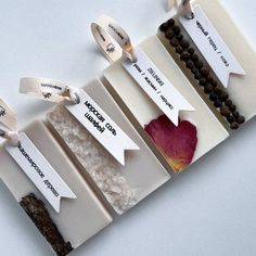 four different types of soaps with labels attached to them on a white table top