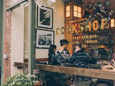 people sitting at tables in front of a store window