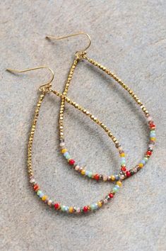 two pairs of beaded hoop earrings sitting on top of a gray carpeted floor