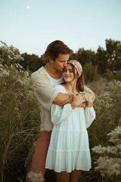 a man and woman hugging in the middle of tall grass