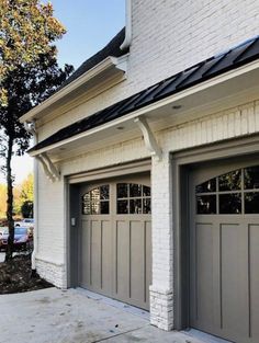 two garage doors are open in front of a white brick building