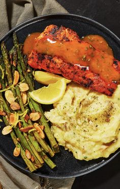 a plate with asparagus, mashed potatoes and salmon on it next to some sauce