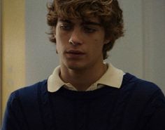 a young man with curly hair wearing a sweater