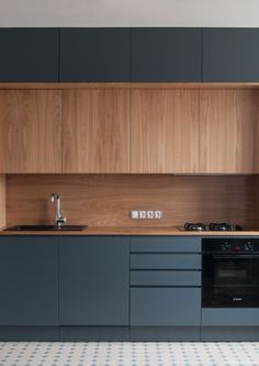 an empty kitchen with blue cabinets and white floor tiles on the walls, along with a black stove top oven