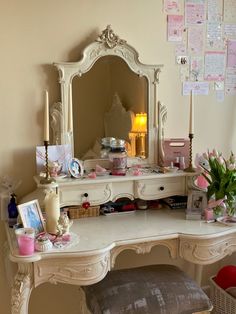 a white desk with a mirror, stool and pictures on the wall