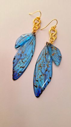 two blue earrings with gold chains hanging from them