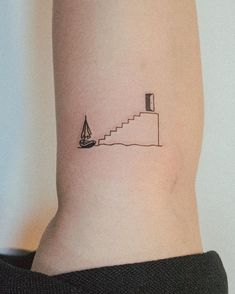 a person with a small tattoo on their arm that has a boat in the water