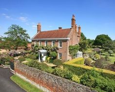 an old brick house surrounded by hedges and trees