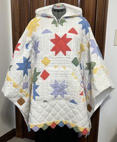 a white quilted jacket with colorful stars hanging on a coat hanger in front of a door