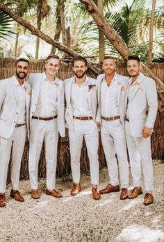 a group of men standing next to each other wearing white suits and brown shoes with palm trees in the background