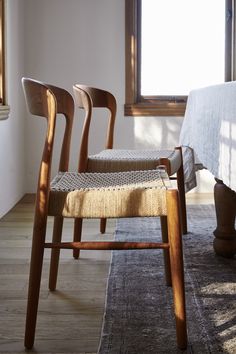 three wooden chairs sitting next to each other on top of a rug in front of a window