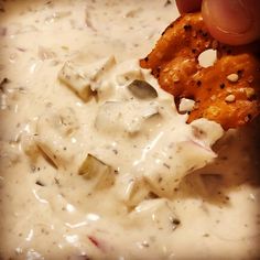 a person dipping some kind of food in a bowl with ranch dressing on it,