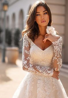 a woman in a wedding dress posing for the camera with her hand on her shoulder