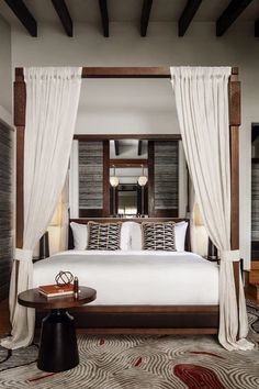 a bedroom with a canopy bed and white drapes on the windows, along with an area rug