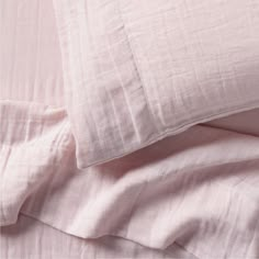 the sheets and pillow cases are made up with pink linens on top of each other