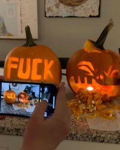 two pumpkins carved to look like jack - o'- lantern faces are being used on a cell phone