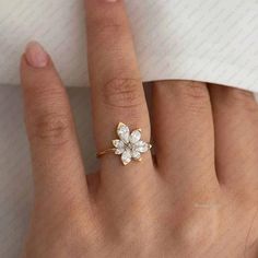 a woman's hand with a ring on it and a flower shaped diamond in the middle