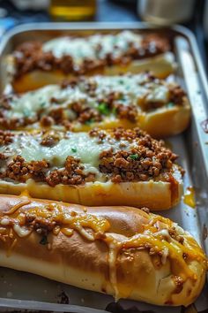 two hotdogs with cheese and meat on them are sitting in a baking pan