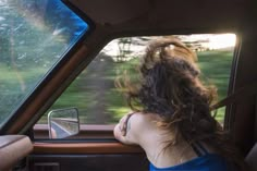 a woman sitting in the driver's seat of a car looking out the window