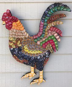 a colorful rooster made out of bottle caps on the side of a building with white siding