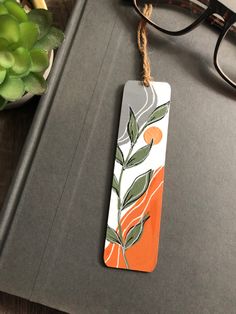 an orange and white bookmark sitting on top of a table next to a pair of glasses