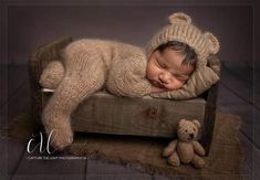 a baby sleeping on top of a wooden crate next to a teddy bear